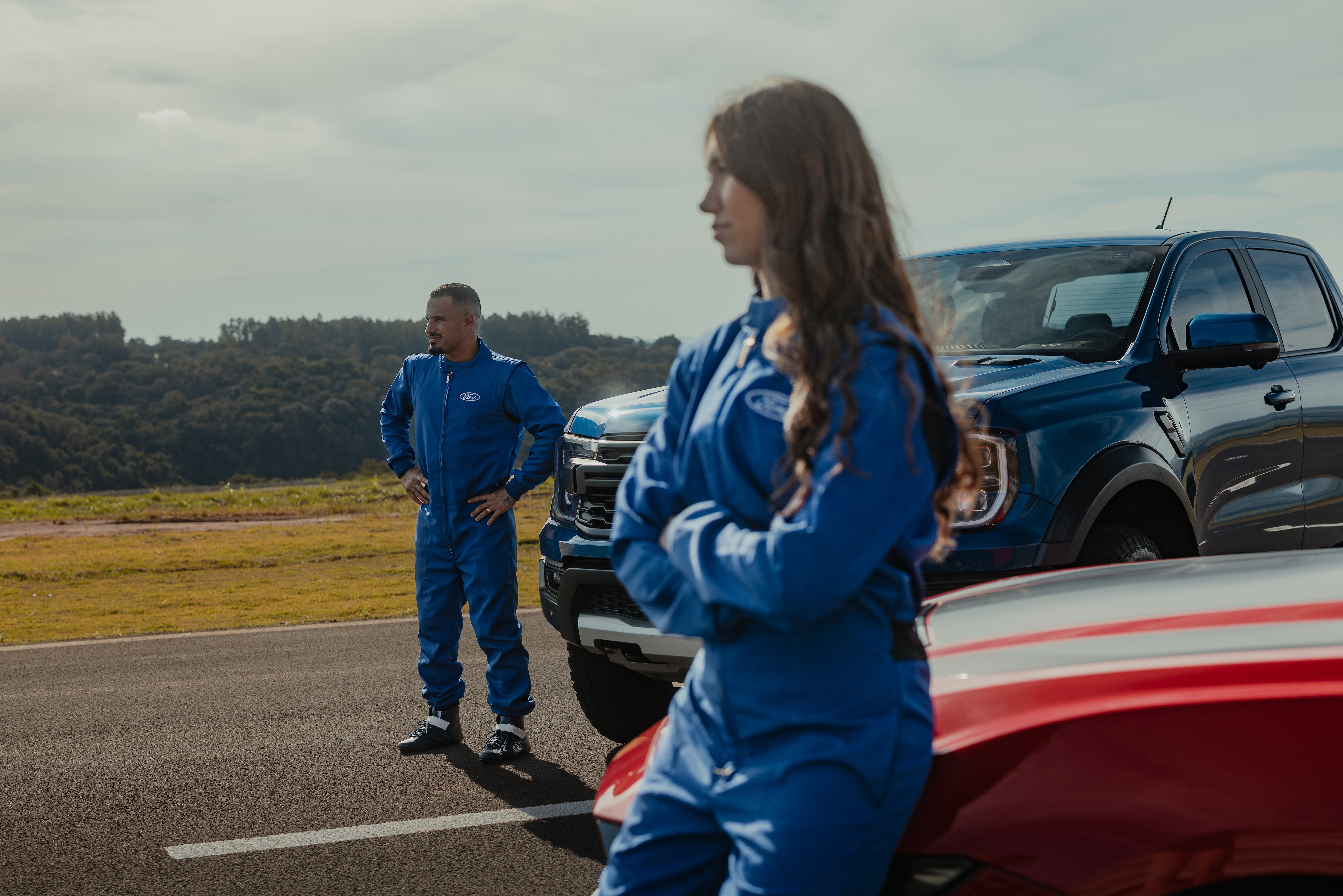 Piloto Rafaela Ferreira e o surfista Ítalo Ferreira na pista com o Mustang Dark Horse vermelho e a picape Ranger Raptor azul
